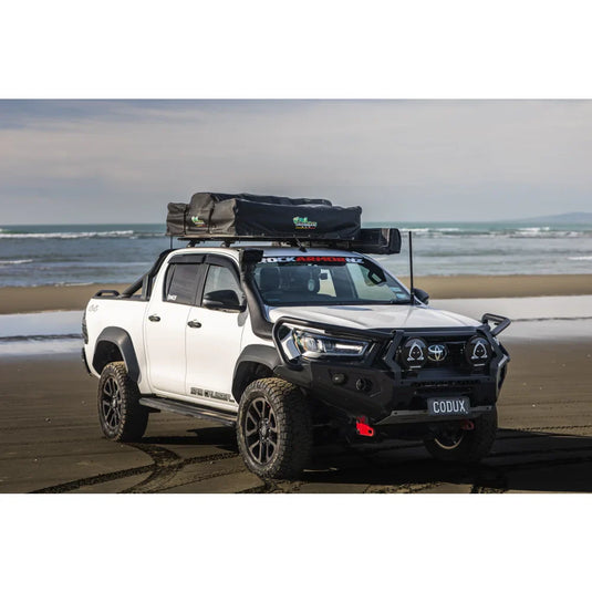 White Toyota Hilux pickup truck with steel hoop bull bar and driving lights for off-road driving