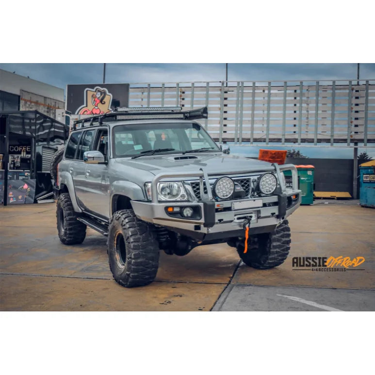 Load image into Gallery viewer, Silver off-road vehicle with oversized tires showcasing Rockarmor premium steel bull bar

