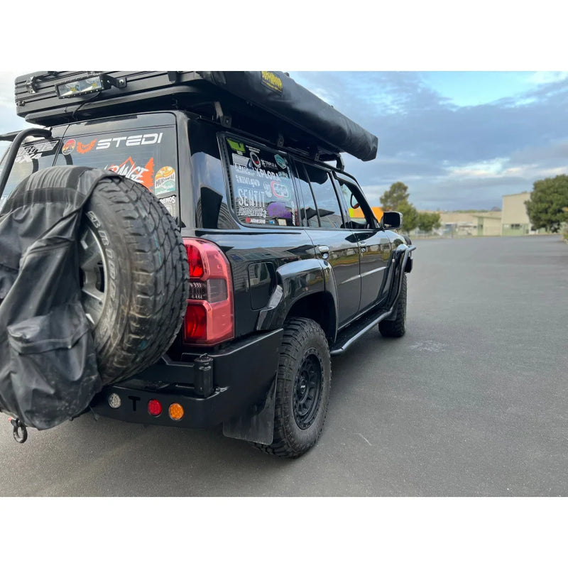Load image into Gallery viewer, Black off-road vehicle with roof tent showcasing Rockarmor steel dual wheel carrier for Nissan Patrol Y61 Gu4 2004-2016 models and spare wheel fitting video
