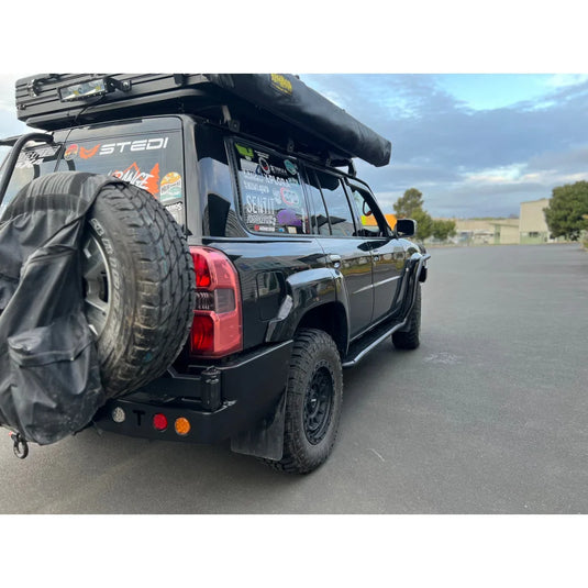 Black off-road vehicle with roof tent showcasing Rockarmor steel dual wheel carrier for Nissan Patrol Y61 Gu4 2004-2016 models and spare wheel fitting video